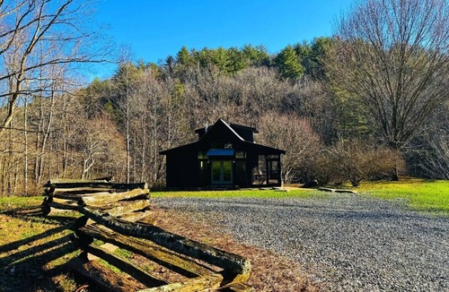 Ellijay Cabin | These charming cabins blend modern design with rustic beauty, offering a peaceful retreat where the main cabin sits one step from a stream, perfect for dining by the water, with stunning views of the surrounding landscape.