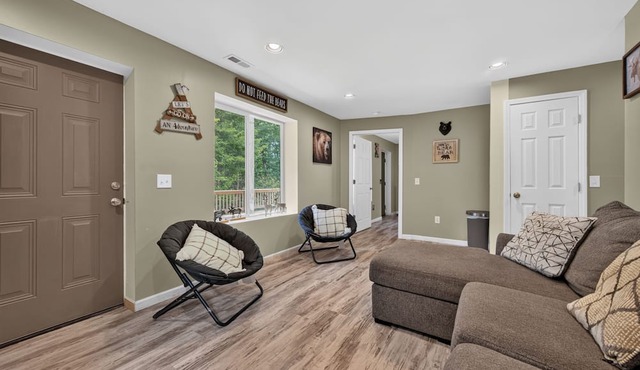 A secluded, multi-level log cabin featuring a spacious wooden deck, open-concept living, a fully equipped modern kitchen, and comfortable sports-themed bunk rooms. in Galax
